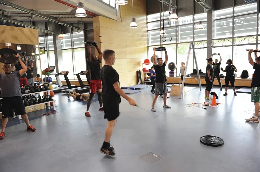 A group of people lifting medium weights in agym.